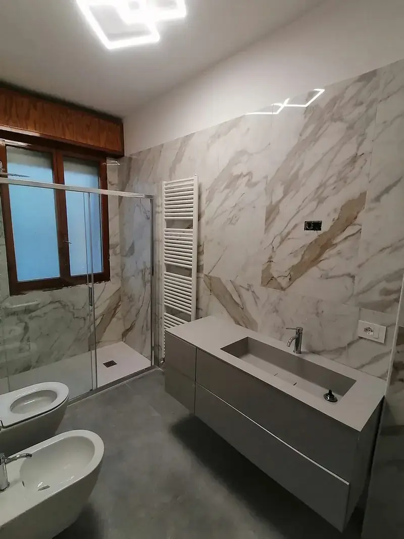 Lo stesso bagno a Riccione rifatto, con rivestimento in marmo e doccia a filo pavimento